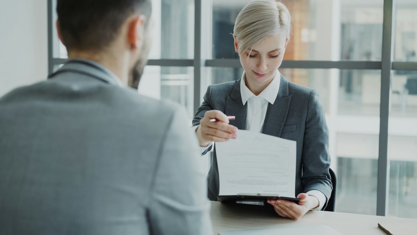 Bizneswoman podaje klientowi dokument i długopis w biurze.
